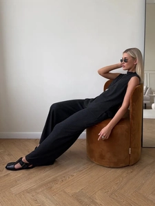 Detail of minimalist sleeveless high-neck top and wide-leg pants in black knit fabric