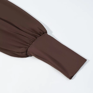 Détail macro des manches de robe marron foncé avec texture côtelée et longs poignets élastiques