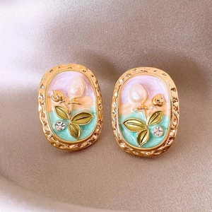 Macro shot of French style tulip enamel earrings with pearls on silk background