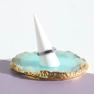 Detailed view of silver ring with round zircon on white cone display stand with blue tray