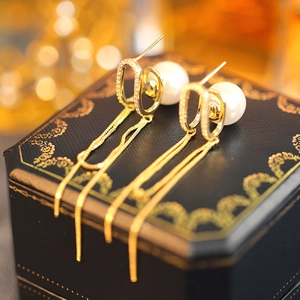 Close-up of gold tassel pearl earrings with pavé zircons on a luxury jewelry box