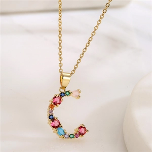 Detail of letter C necklace with colorful gemstones and pink heart pendant on gold chain