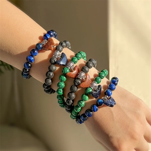 Close-up of stacked beaded bracelets with tiger eye, lava rock and heart pendants