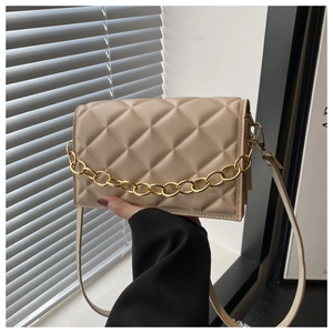Detailed shot of beige quilted faux leather bag with elegant gold chain decoration