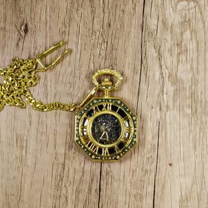 Vintage gold octagonal mechanical pocket watch with hollow dial and Roman numerals on wood