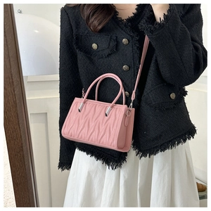 Detailed view of pink pleated handbag featuring wave pattern quilting and dual top handles