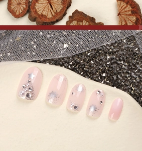 Close-up of pink French press-on nails with silver snowflakes and pearl star decorations