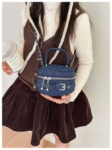 Detail of blue denim quilted round bag with chain strap and leather handle for girls