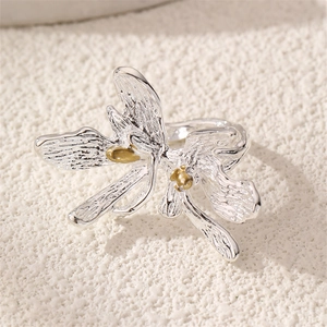 Macro detail of orchid flower ring with brushed silver petals and gold stamen center
