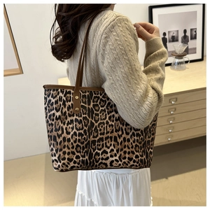 Detail of a large leopard print tote bag with brown straps worn in a lifestyle setting