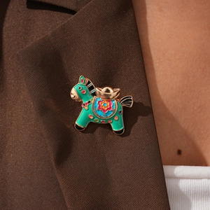 Detailed view of horse-shaped brooch with enamel finish pinned on a brown suit lapel