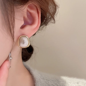 Close-up of vintage resin trapezoid earring with gold metal frame on a model ear