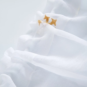 Detail of white cafe curtain featuring fine gold crown embroidery on sheer fabric texture