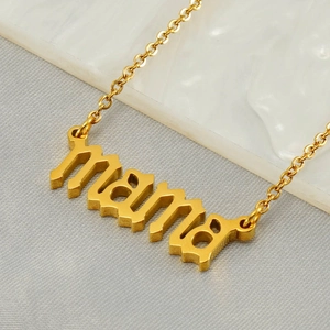 Golden MAMA necklace in stainless steel on white marble and grey fabric background