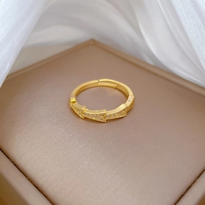 Bamboo-style zircon gold ring on a beige jewelry box with white silk fabric backdrop