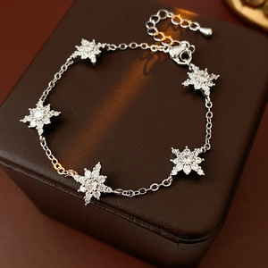 Détail d'un bracelet en argent avec breloques d'étoiles et zircons sur écrin