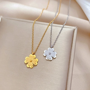 Close-up of gold and silver four-leaf clover necklaces with a frosted finish on a stand