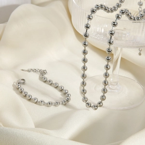 Minimalistisches 6mm Perlen Schmuckset mit Kette und Armband auf weißem Satin