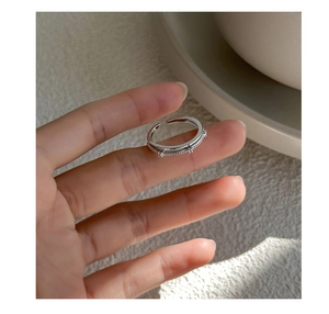 Detailed close-up of double-layer silver ring with zircons and twisted rope texture
