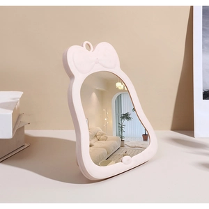 Détail d'un miroir de maquillage en forme de cloche avec cadre rose et nœud décoratif