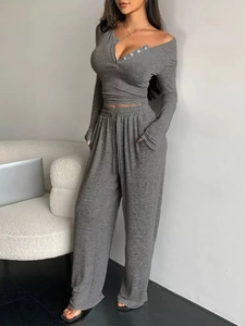 Detail view of the V-neck buttoned top and grey knitted trousers with pockets on the model