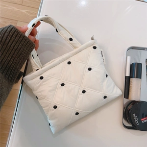 Dettaglio di una borsa trapuntata bianca a pois neri su un tavolo dallo stile minimal
