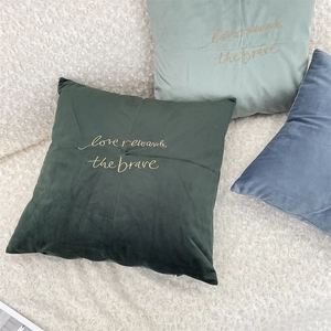 Detailed embroidery on velvet pillow covers in green and blue with gold lettering
