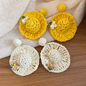 Detailed view of handmade straw hat earrings with woven textures and 3D floral accents