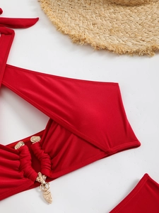Macro detail of red bikini top with golden metal hardware and elegant beach hat decor