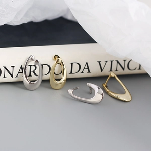 Detailed view of geometric teardrop earrings in polished gold and silver metal finishes