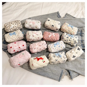 Flat lay of small quilted cotton makeup bags with floral and cherry patterns on denim jacket