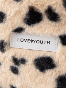 Macro detail of faux fur leopard print fabric with Love Youth brand label on the bag