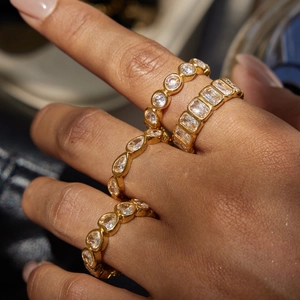 Detail view of four gold-plated stacking rings with different zircon gemstone shapes
