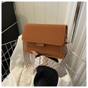 Dettaglio borsa a tracolla marrone con ampia tracolla beige a rombi e finiture in oro lucido