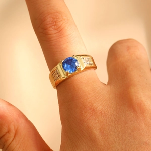Nahaufnahme eines Herren-Goldrings mit großem blauem Zirkon und Mikro-Pavee-Verzierung