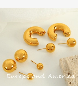 Detail of gold titanium steel jewelry set with bold C-hoops and sphere stud earrings
