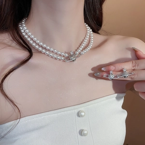 Macro detail of double-layer pearl necklace with sparkling planet planet pendant