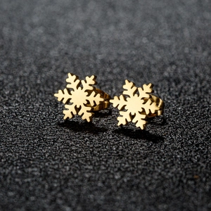 Macro view of gold snowflake stud earrings showing metallic texture and detailed edges