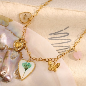 Close-up of 18K gold plated heart charms with dried flowers and cubic zirconia on shell