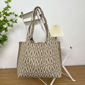 Detail of knitted tote bag with brown and beige wave geometric texture on chair