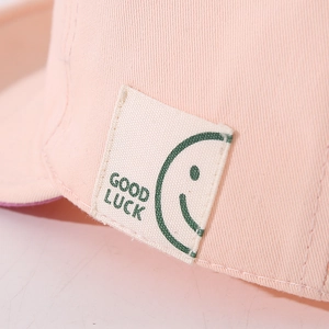 Pink cotton baseball cap for babies with Good Luck lettering and smiley face patch