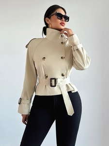 Detail of beige short double-breasted trench coat with black belt and cuff strap accents