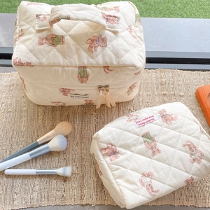 Detail of quilted cotton cosmetic bags with cute bear prints on a woven mat