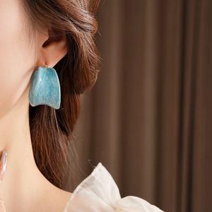 Close-up of blue marble resin hoop earrings with artistic irregular surface on model