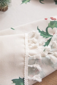 Detailed texture of cotton linen Christmas tablecloth with holly patterns and tassels