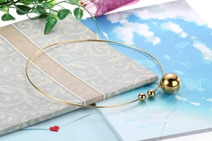Collier ras du cou doré en acier inoxydable avec pendentifs boules sur un livre vintage