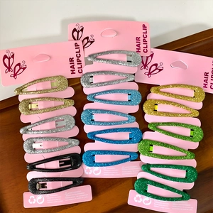 Set of colorful glitter snap clips for girls on pink display cards on wooden surface