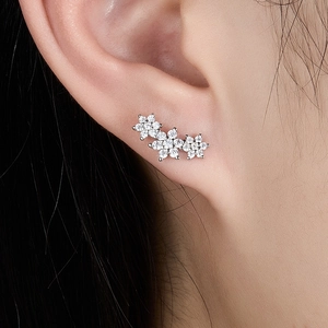 Macro shot of silver flower earrings with zircon inlays worn on a model's ear