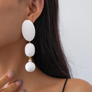 Détail de boucles d'oreilles longues en acrylique blanc avec maillons dorés