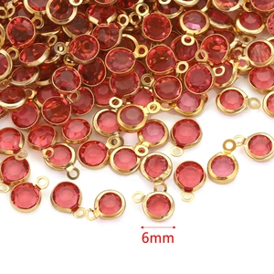 Close-up of 6mm red crystal birthstone charms with golden hoops for DIY jewelry making